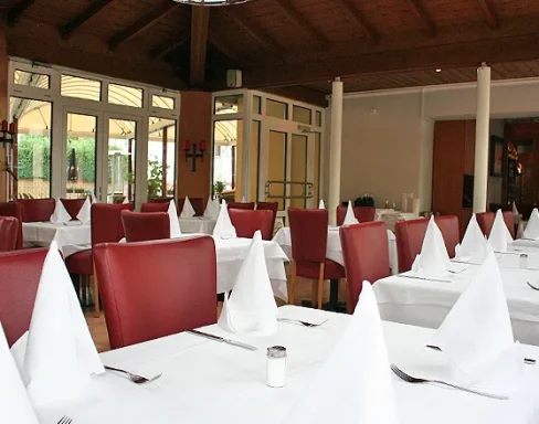 Elegante Restaurant mit roten Stühlen und weiß eingedeckten Tischen.