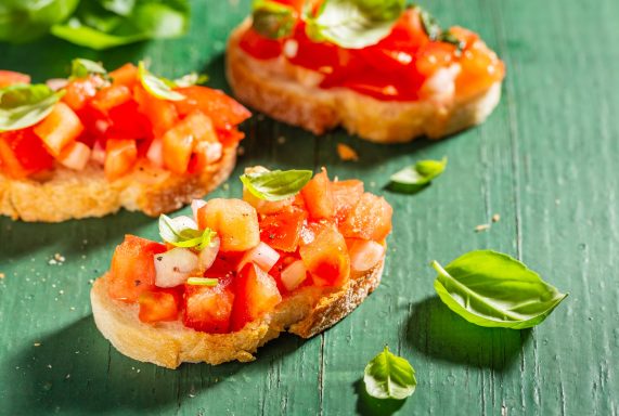 Bruschetta mit frischen Tomaten, Olive und Basilikum auf knusprigem Brot.